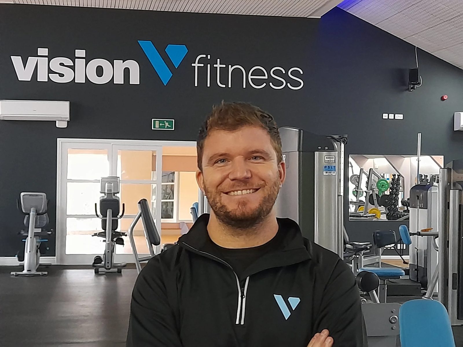 Vision Health coach in front of the Vision Fitness sign