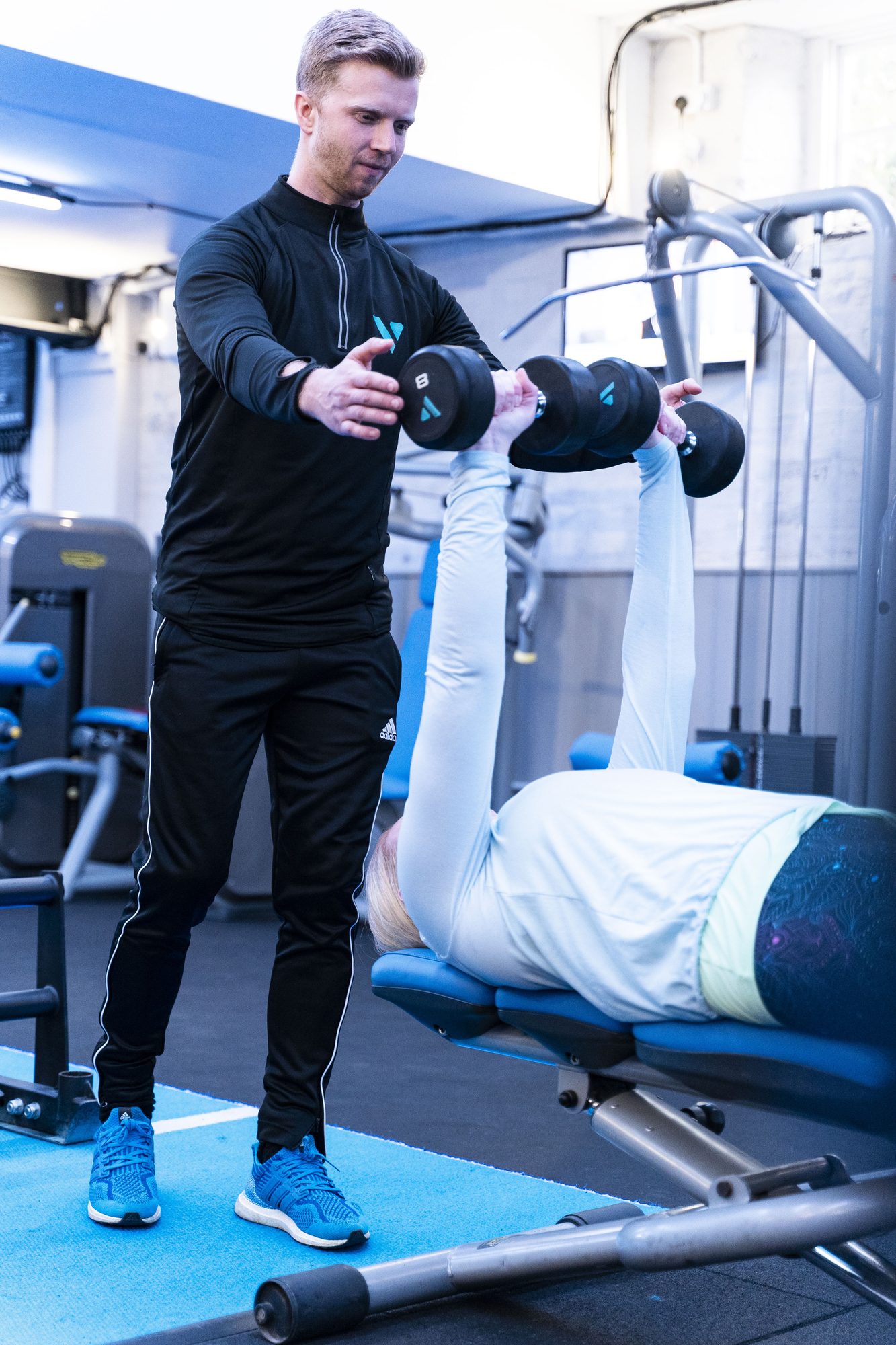 Coach spotting a member during a bench press