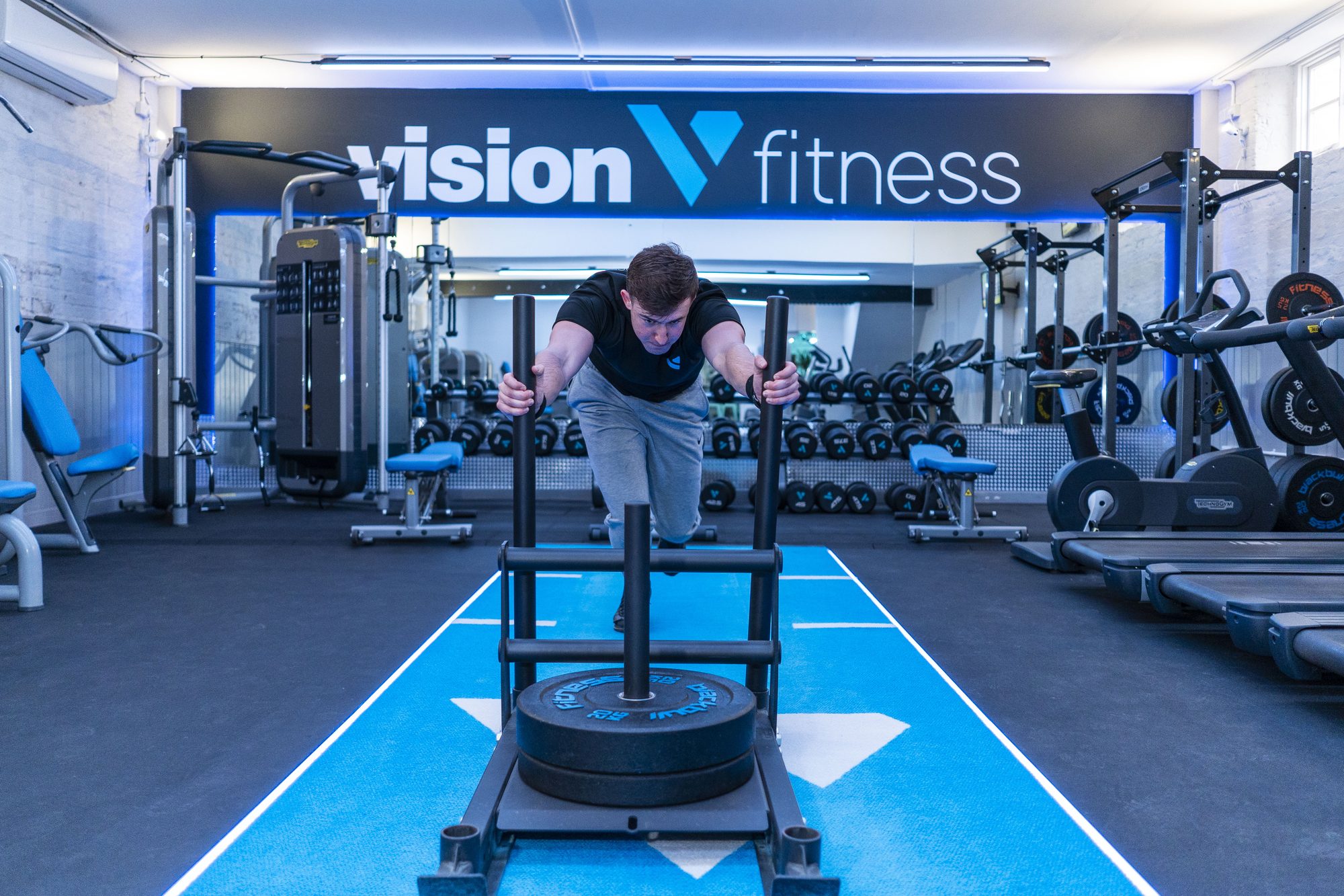 Sled push under the Vision Fitness brand wall